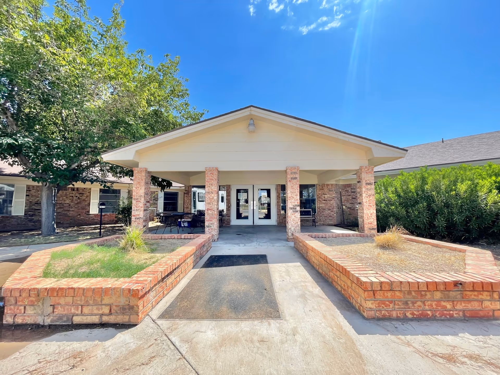 Entrance of Trans-Pecos Nursing and Rehabilitation featuring a covered porch and garden area.