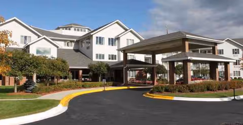 Exterior view of Holiday Blue Water Lodge, a white senior living facility with a covered entrance.