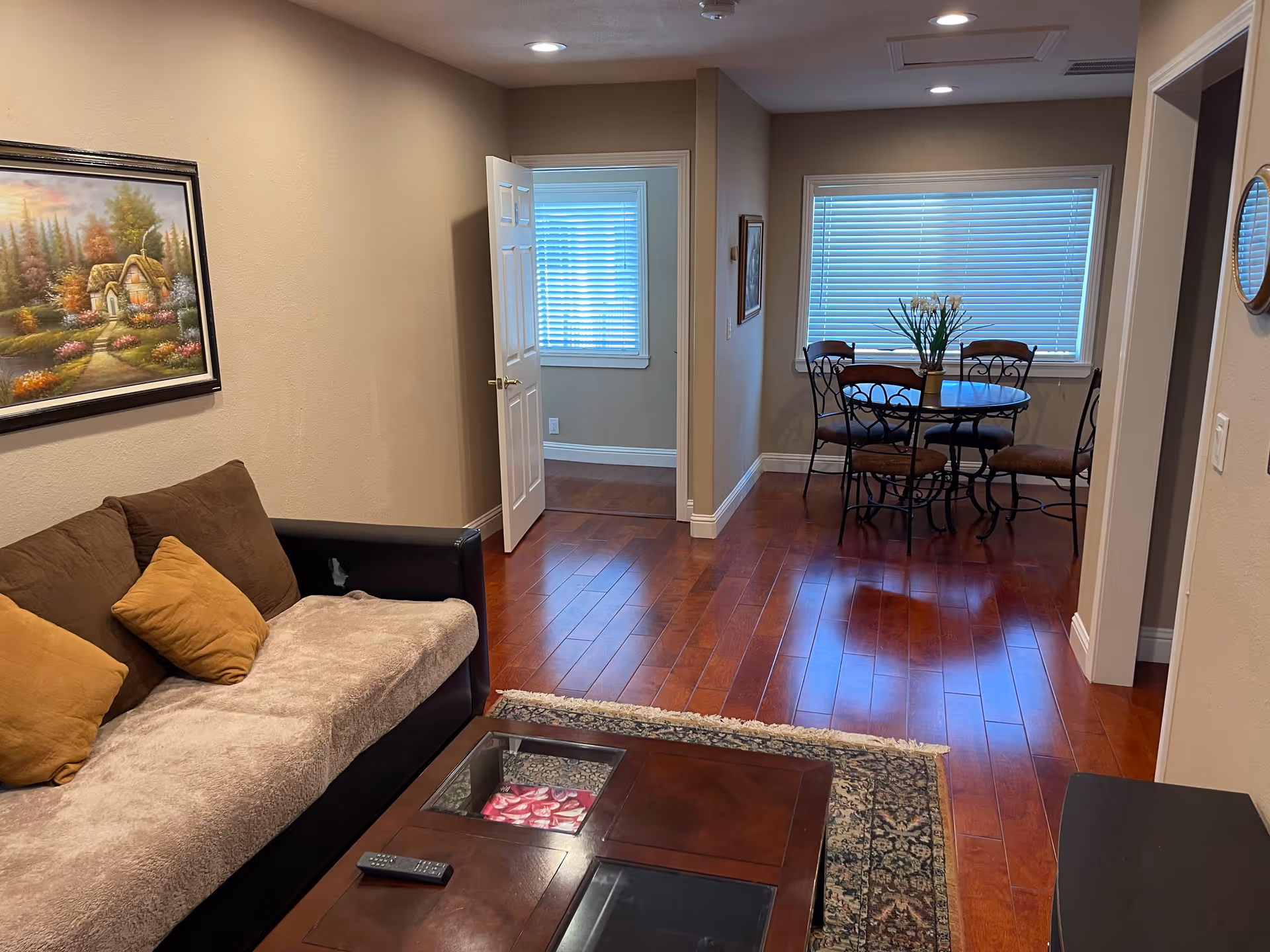 Cozy living room with sofa, coffee table, rug, and a dining area in back.