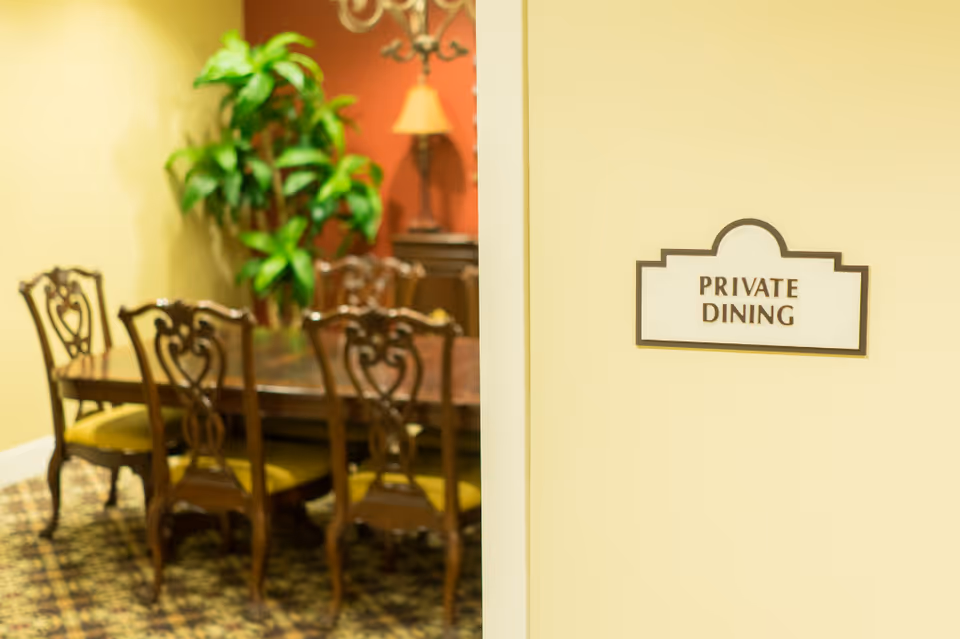 A wall sign reading "PRIVATE DINING" beside a doorway opening into a formal dining room with a wooden table and chairs.