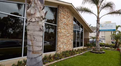 Exterior view of Beachside Nursing Center with stone facade, palm trees, and manicured landscaping.