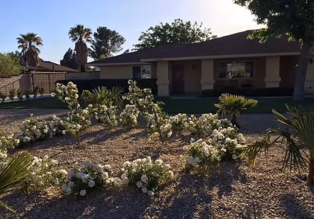 Single-story senior living facility with a front entrance and white flowering shrubs in the landscaping.