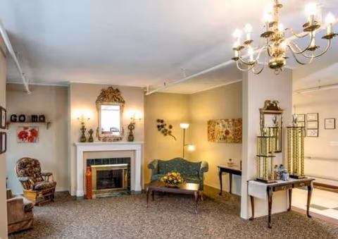 Spacious senior living lounge featuring a fireplace, seating area, chandelier, and decorative furnishings.