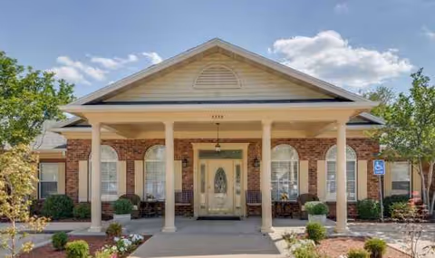 Front view of a brick senior living facility with a covered entrance and columns.