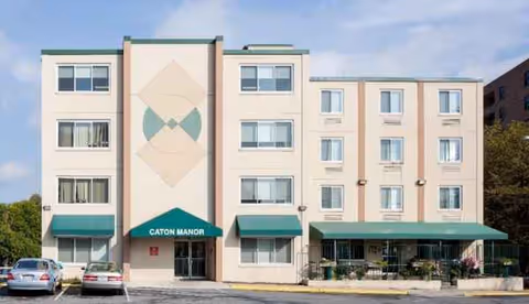 Four-story beige senior living building with green awnings and a parking lot