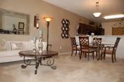 Open living and dining area with a sofa, decorative coffee table, dining set and a kitchen bar in the background.