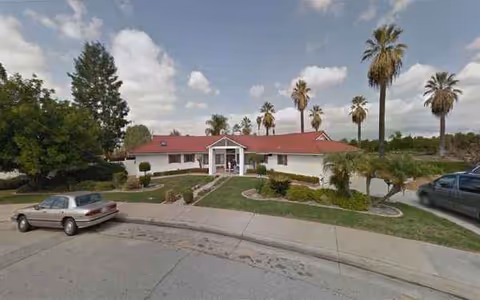 Meadowbrook Homes exterior: single-story building with red roof, landscaped front, and palm trees.