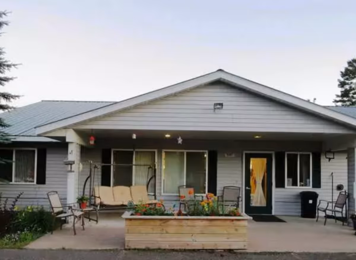 Single-story building entrance with a covered porch, outdoor seating, and a raised planter box.