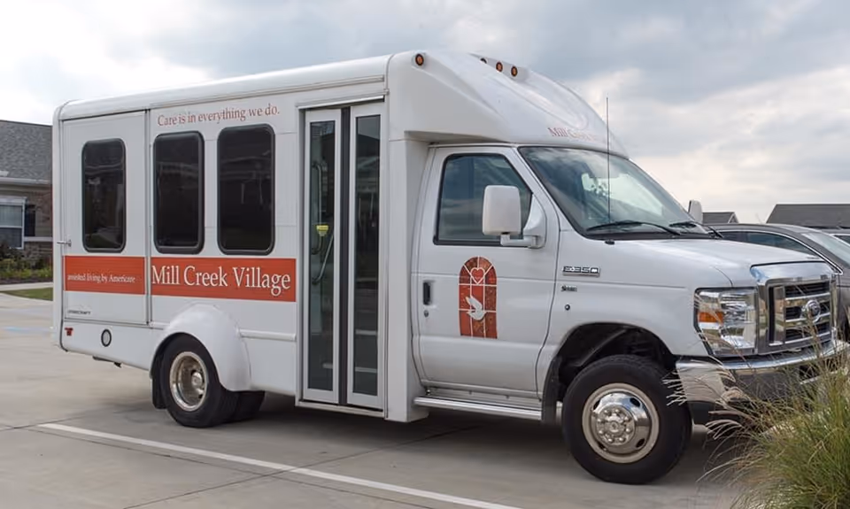 White Mill Creek Village senior living shuttle bus parked outside the facility.