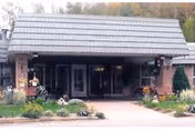 Entrance of Norlite Nursing Center with a covered driveway, brick pillars, and landscaped flower beds on either side of the walkway.