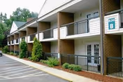 Exterior view of a two-story senior living building with balconies, ground-level patios, and landscaping.