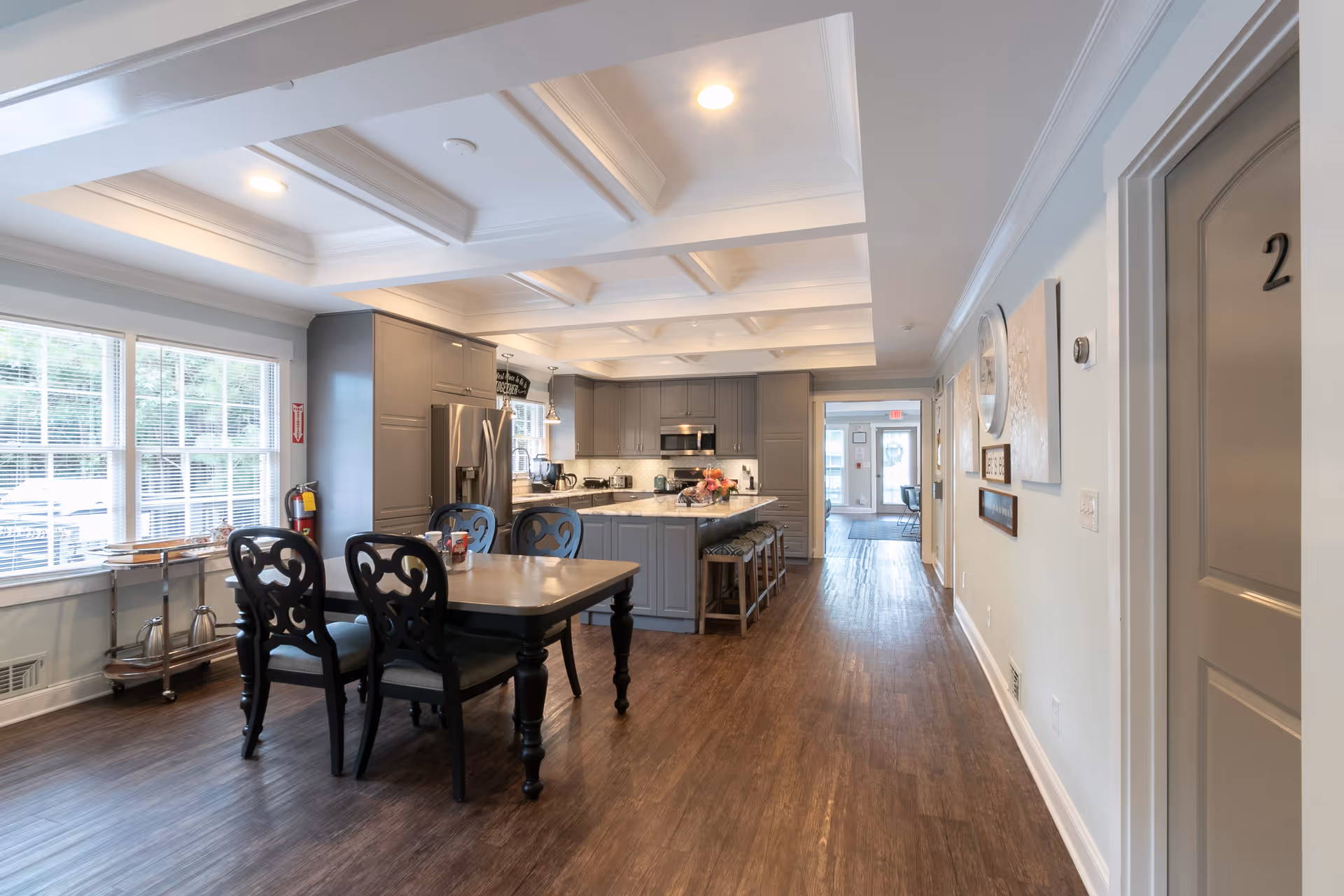 Bright open kitchen and dining area with a central island, dining table, and large windows.
