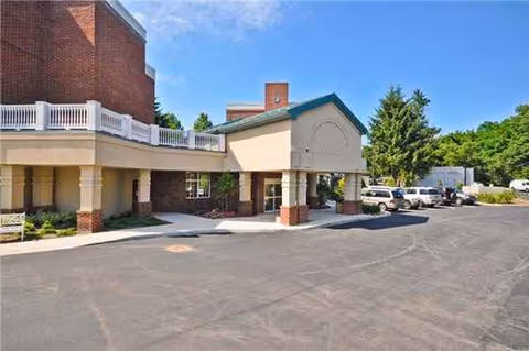 Exterior view of Cold Spring Hills entrance with driveway, cars, and covered drop-off area.