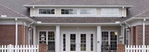Exterior view of a senior living facility with brick columns, white trim, and a covered entry.