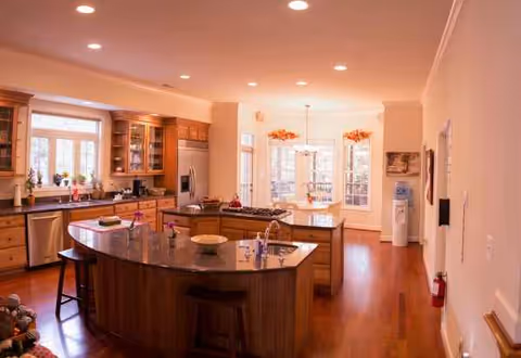 Bright senior living kitchen with central island, wooden cabinets, and dining area.