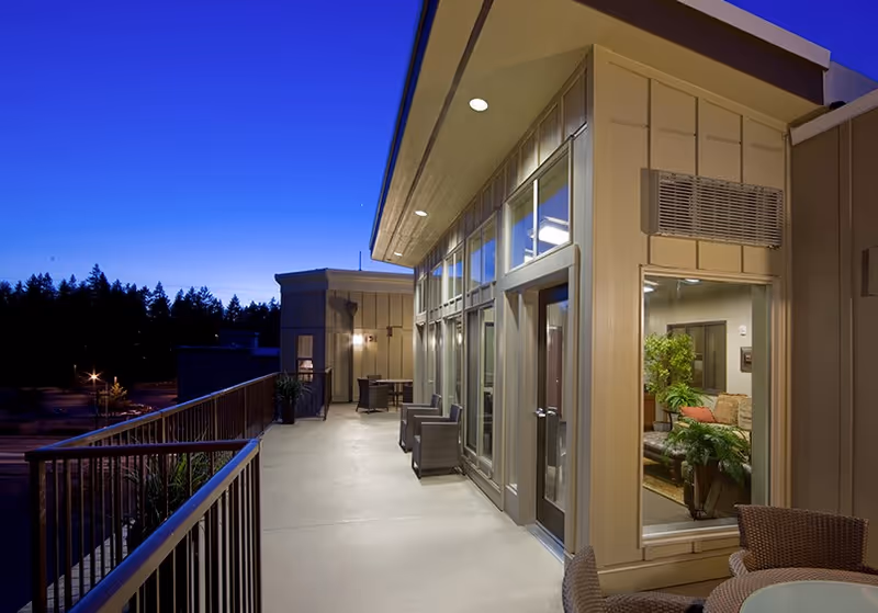 Evening exterior balcony of The Blakely Echo Lake with glass doors and seating.