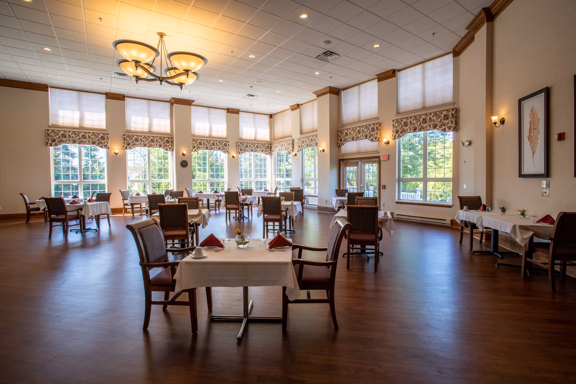 Spacious dining room with multiple set tables, large windows, and high ceilings.