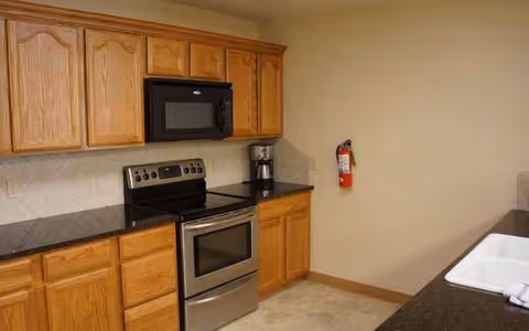 Residential kitchen featuring wooden cabinets, stove, microwave, coffee maker, and sink.