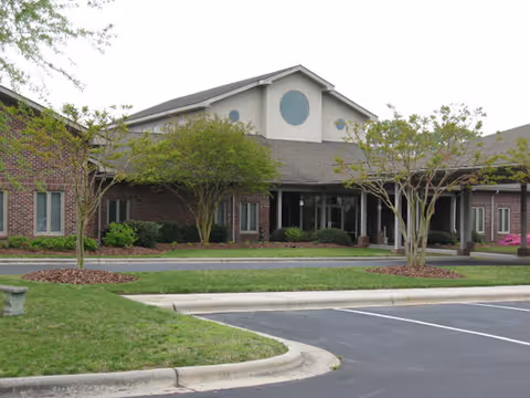 Single-story brick senior living facility with front entrance and manicured landscaping.