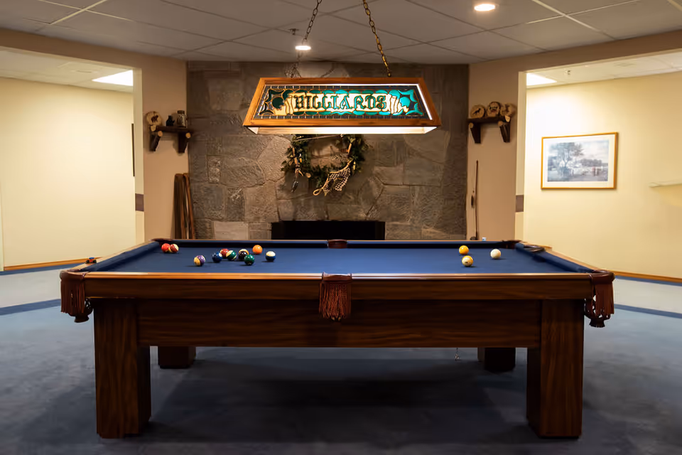 Indoor game room featuring a billiards table with a blue felt top and a stained-glass "BILLIARDS" light fixture.