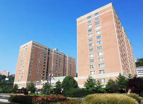 Two tall brick Waterford Towers buildings with manicured landscaping under a clear blue sky.