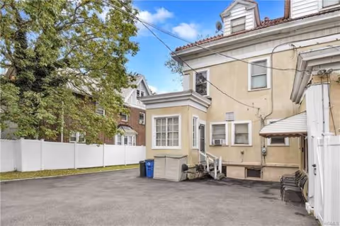 Exterior view of Chester Hill Adult Home: beige building with stairs, fence, and trees.
