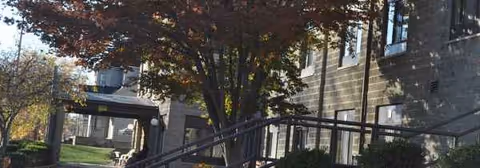 Exterior view of Grafton Oaks Rehabilitation and Nursing Center with trees and a covered entrance.