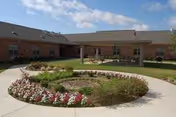Exterior view of Trail Lake Nursing and Rehabilitation with a circular flower bed and walkway.