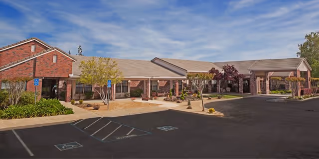Front view of Oakwood Village Assisted Living and Memory Care facility with parking and walkway