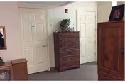 Carpeted interior hallway with closed doors, a wooden chest of drawers, an armoire, and a potted plant.