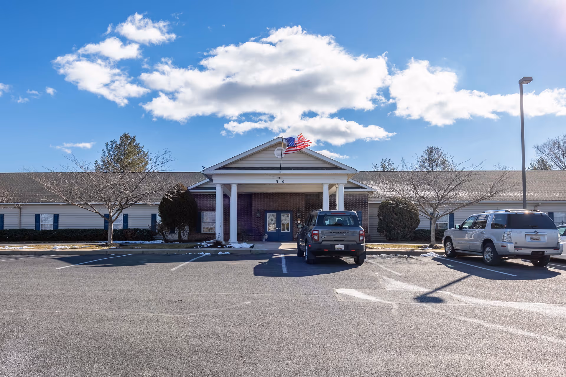 Front view of Commonwealth Senior Living at Hagerstown with entrance, flag, and parking