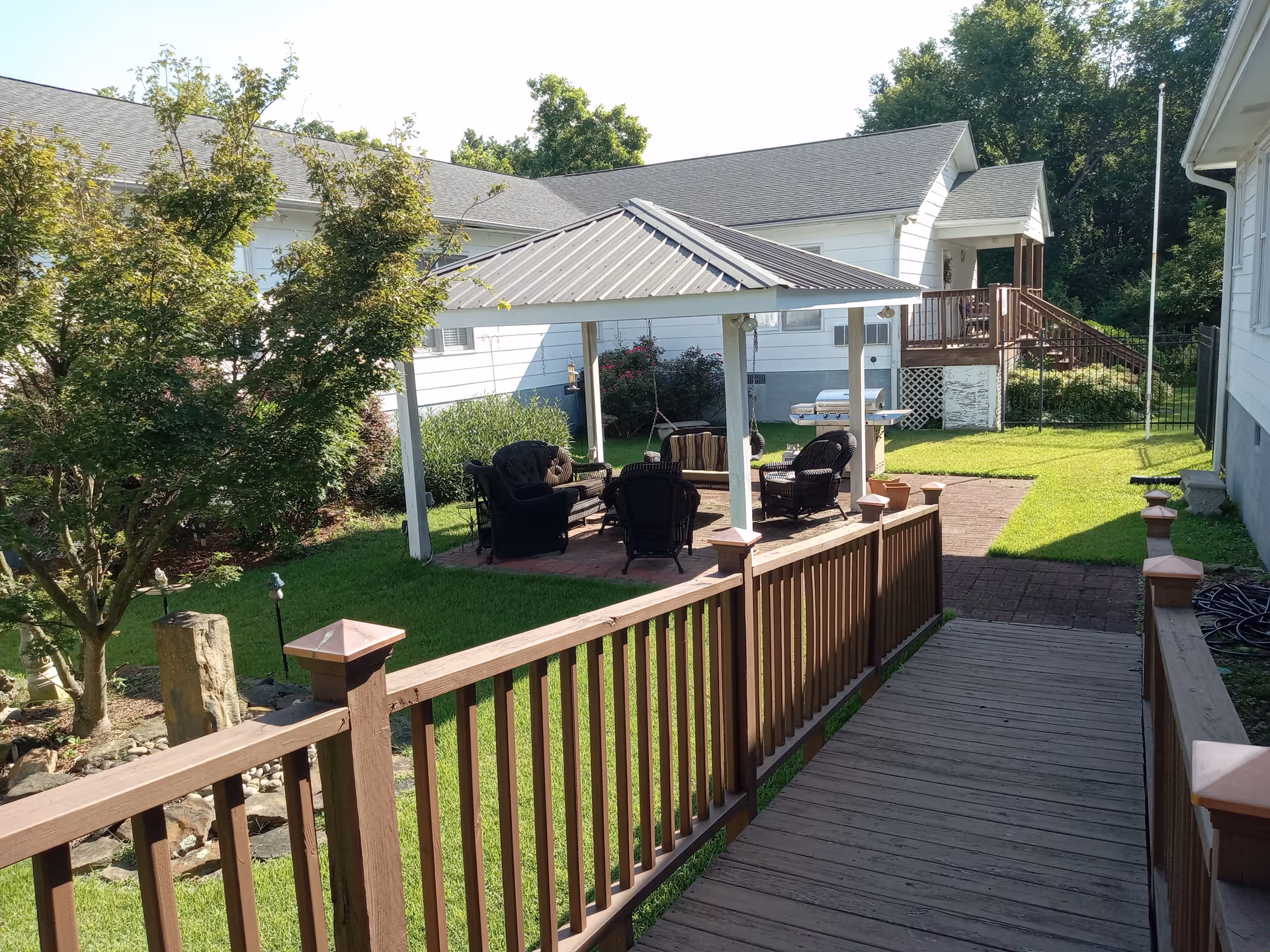 Outdoor courtyard with a covered gazebo, patio seating, and a wooden ramp leading to the area.