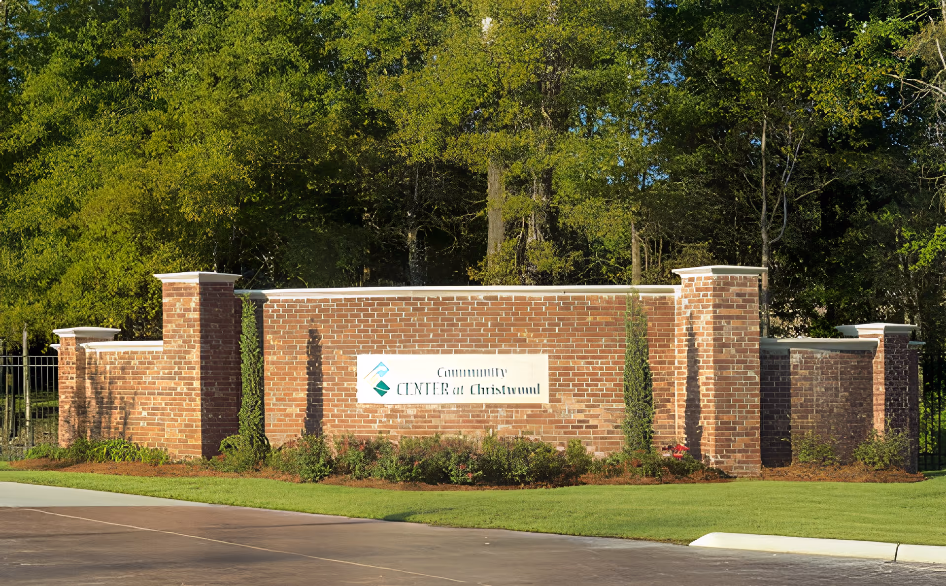 A brick entrance sign for the Community Center at Christwood Retirement Community, surrounded by green grass and trees in the background.