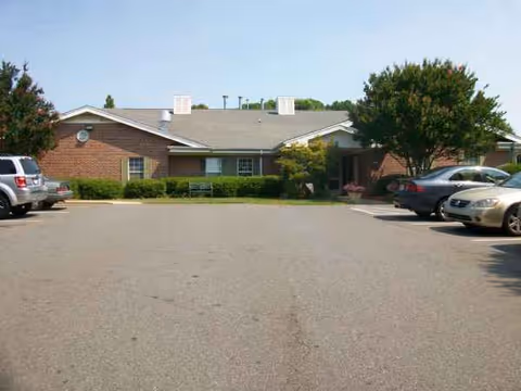 Exterior view of Preston House senior living facility with parked cars and trees