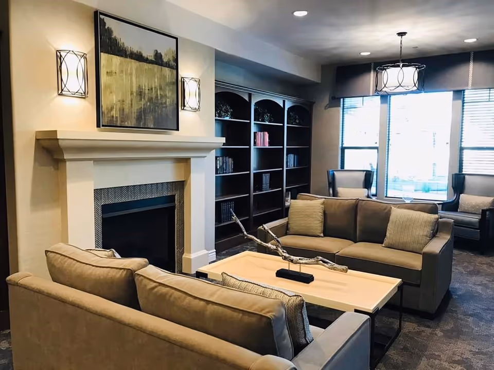 Cozy lounge area with sofas, a coffee table, fireplace, built-in bookshelves and large windows.