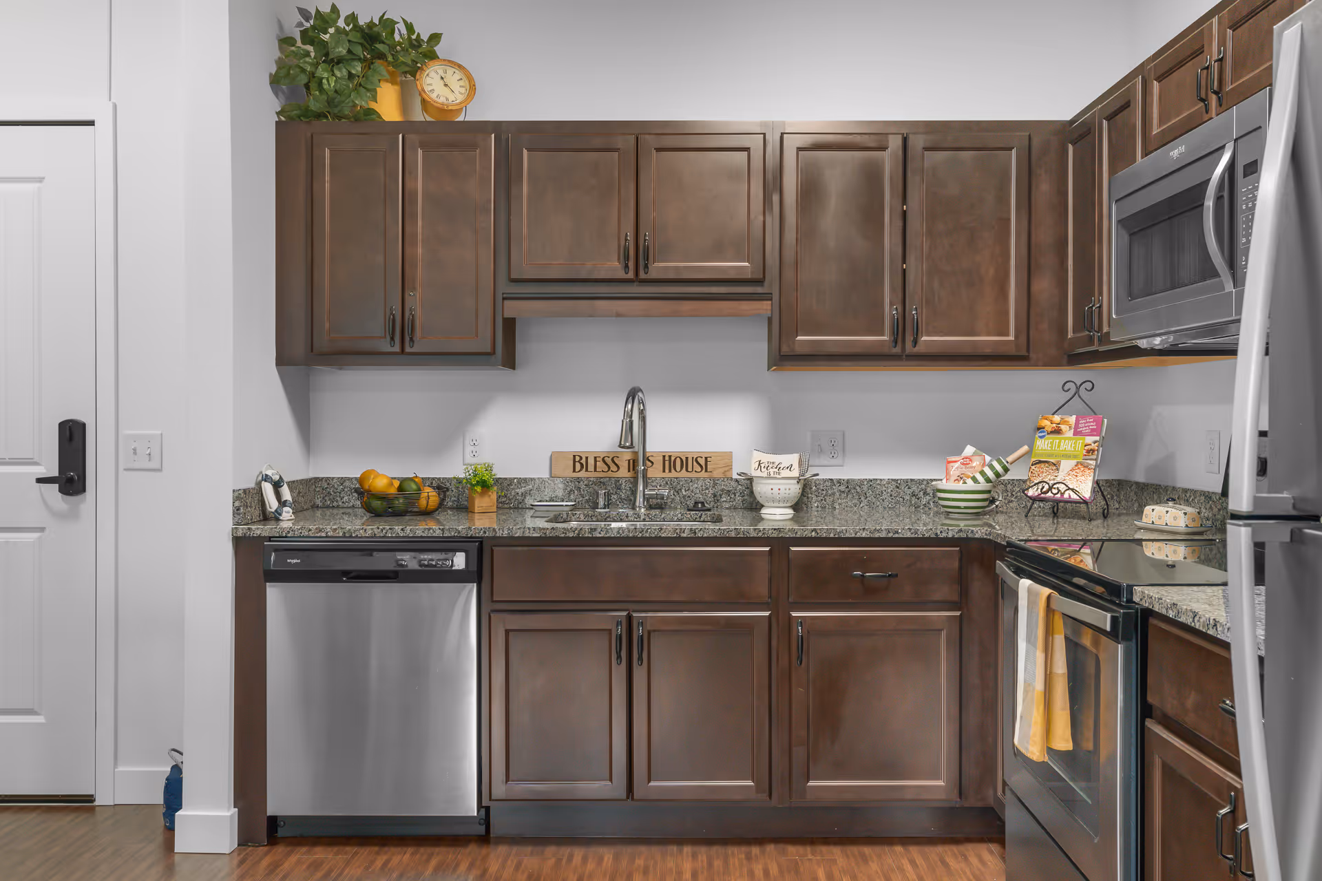 Kitchen with dark wood cabinets, granite countertops, stainless steel appliances, and a sink centered beneath upper cabinetry.