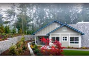 Front exterior of a single-story lodge-style building with a landscaped yard, walkway, and trees behind it.