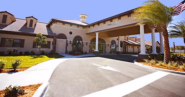 Exterior view of Palm Bay Memory Care building with entrance canopy and palm trees.