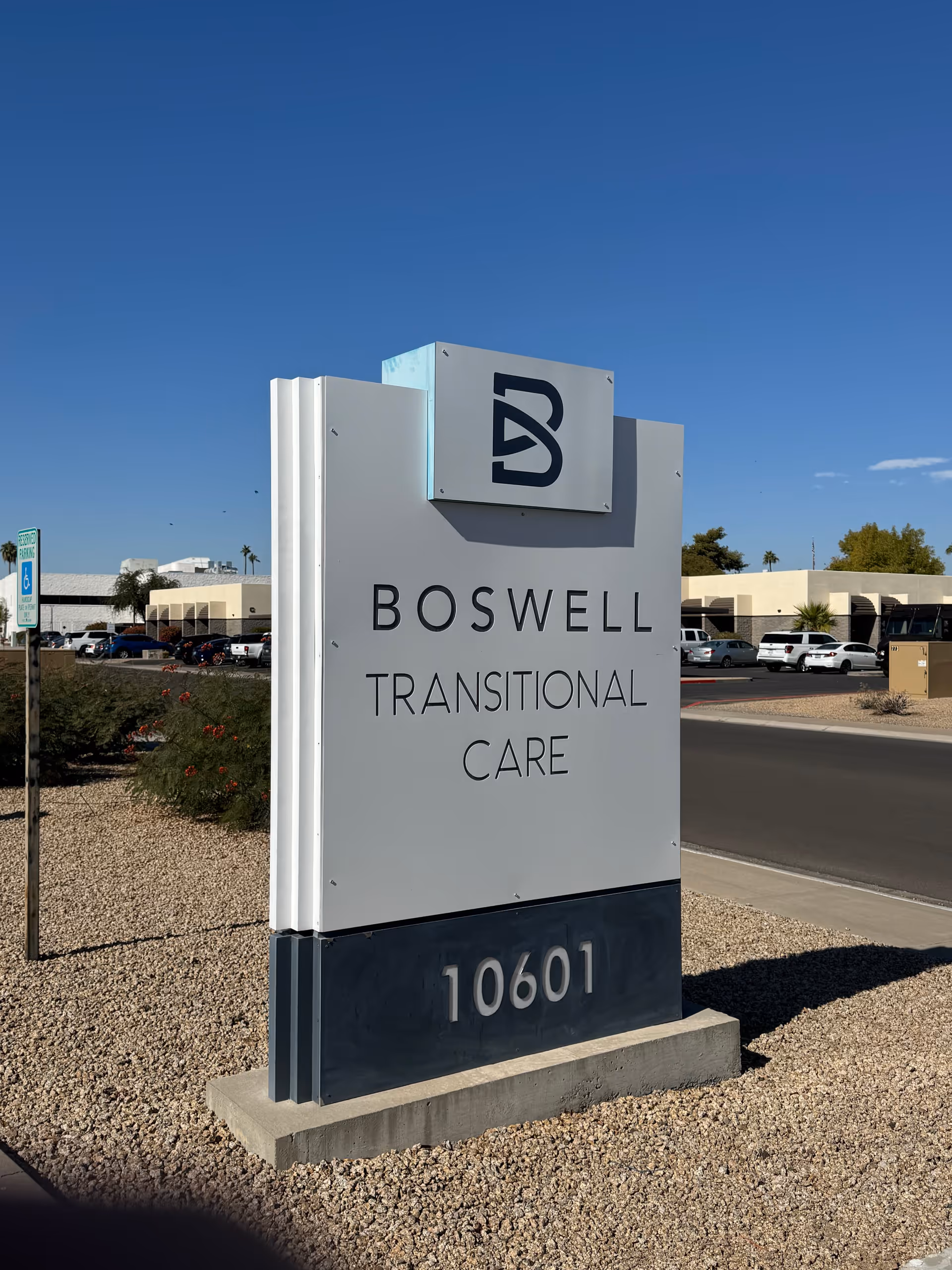 Freestanding sign reading "Boswell Transitional Care" with the address 10601 in front of the facility under a clear blue sky.