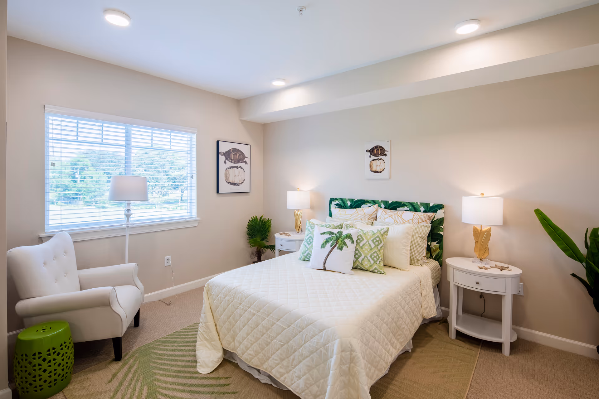 Bright, coastal-themed bedroom with a bed, bedside tables and lamps, an armchair by a window, and tropical accents.