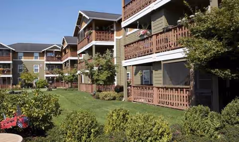 Exterior view of The Springs at Clackamas Woods senior apartments with balconies and lawn.