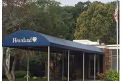 Blue canopy entrance labeled Heartland over glass doors with trees nearby.