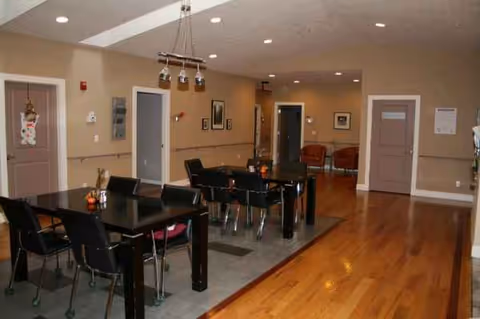 Interior common area at All Comfort Residential Care with dark dining tables and chairs.