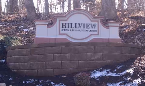 Hillview Health and Rehabilitation Center sign atop curved brick planter with trees behind