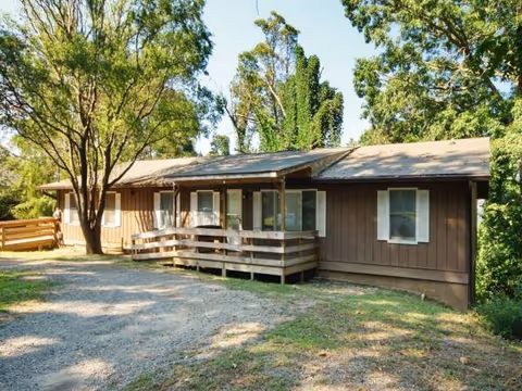 A single-story brown wooden care home with a front porch and surrounding trees.