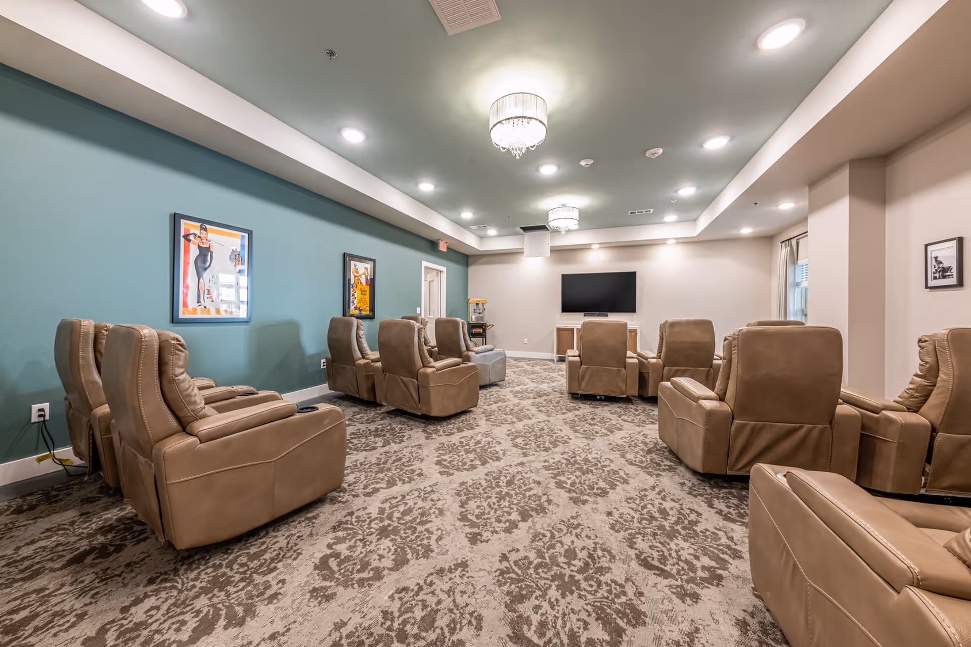 Spacious senior living lounge with beige recliners arranged around a central TV