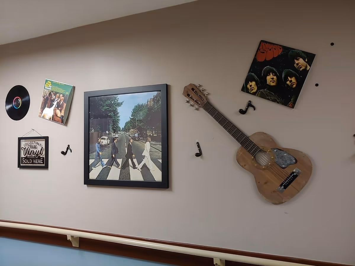 Wall decorated with music-themed items including a vinyl record, album covers, a framed sign that reads 'Collectible Rare Vinyl Records Sold Here', a framed picture of The Beatles crossing Abbey Road, a wooden guitar, and musical note decorations.