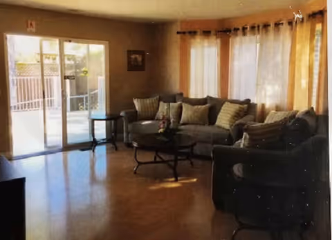 Interior living room with sectional sofas, coffee table, and sliding glass doors.