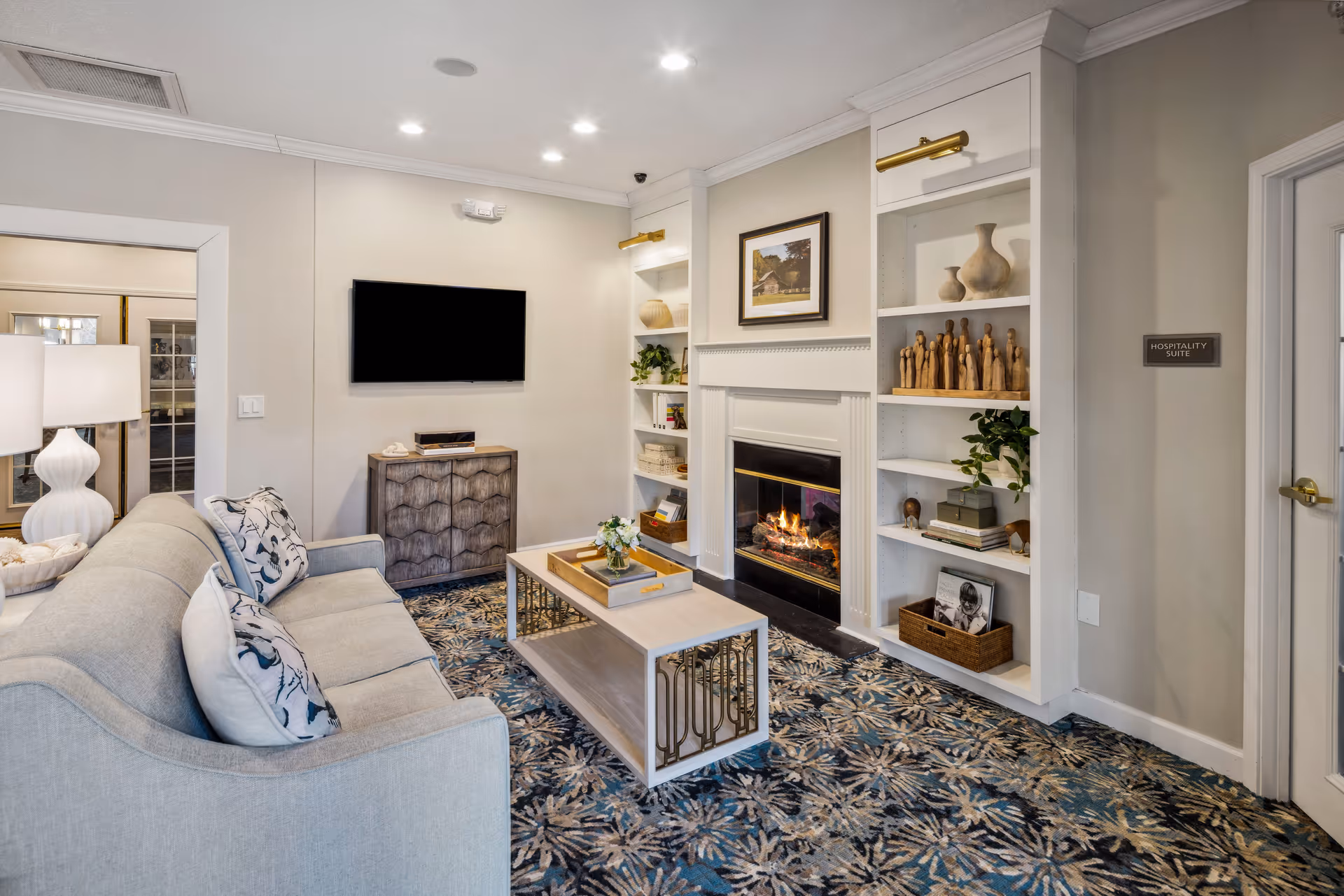 Cozy living room with a sofa, coffee table, fireplace flanked by built-in shelves, and a wall-mounted TV.