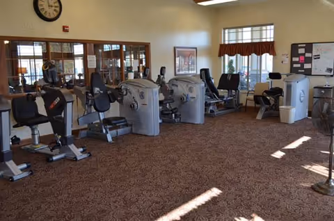 A spacious fitness room with multiple recumbent exercise bikes and cardio machines arranged on a carpeted floor.